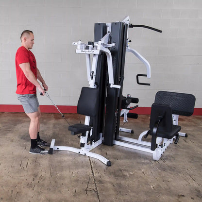 Man using Body-Solid home gym machine in a red shirt and gray shorts.