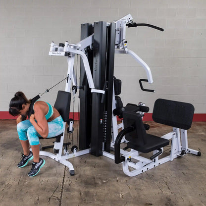 Woman exercising on Body-Solid home gym, wearing blue workout attire.