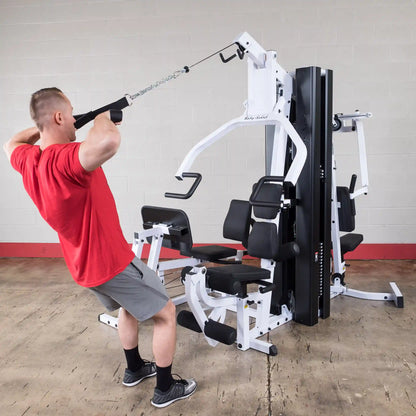 Man using Body-Solid home gym for tricep exercise, featuring black padded seats.