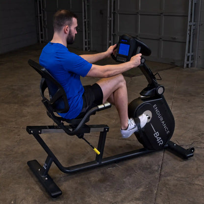 Man using Endurance B4R recumbent exercise bike in a garage gym.