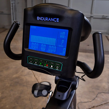 Endurance exercise bike display with blue digital screen and black handlebars.