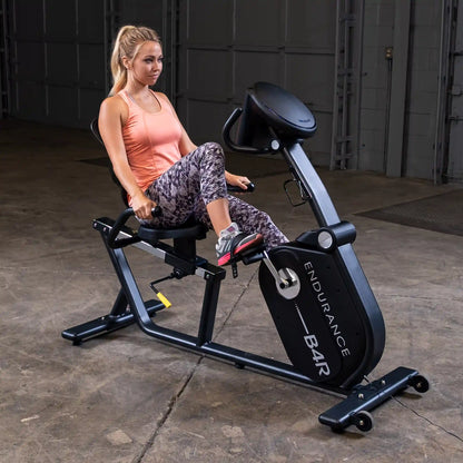 Woman using Endurance B4R recumbent bike with black frame in a gym.