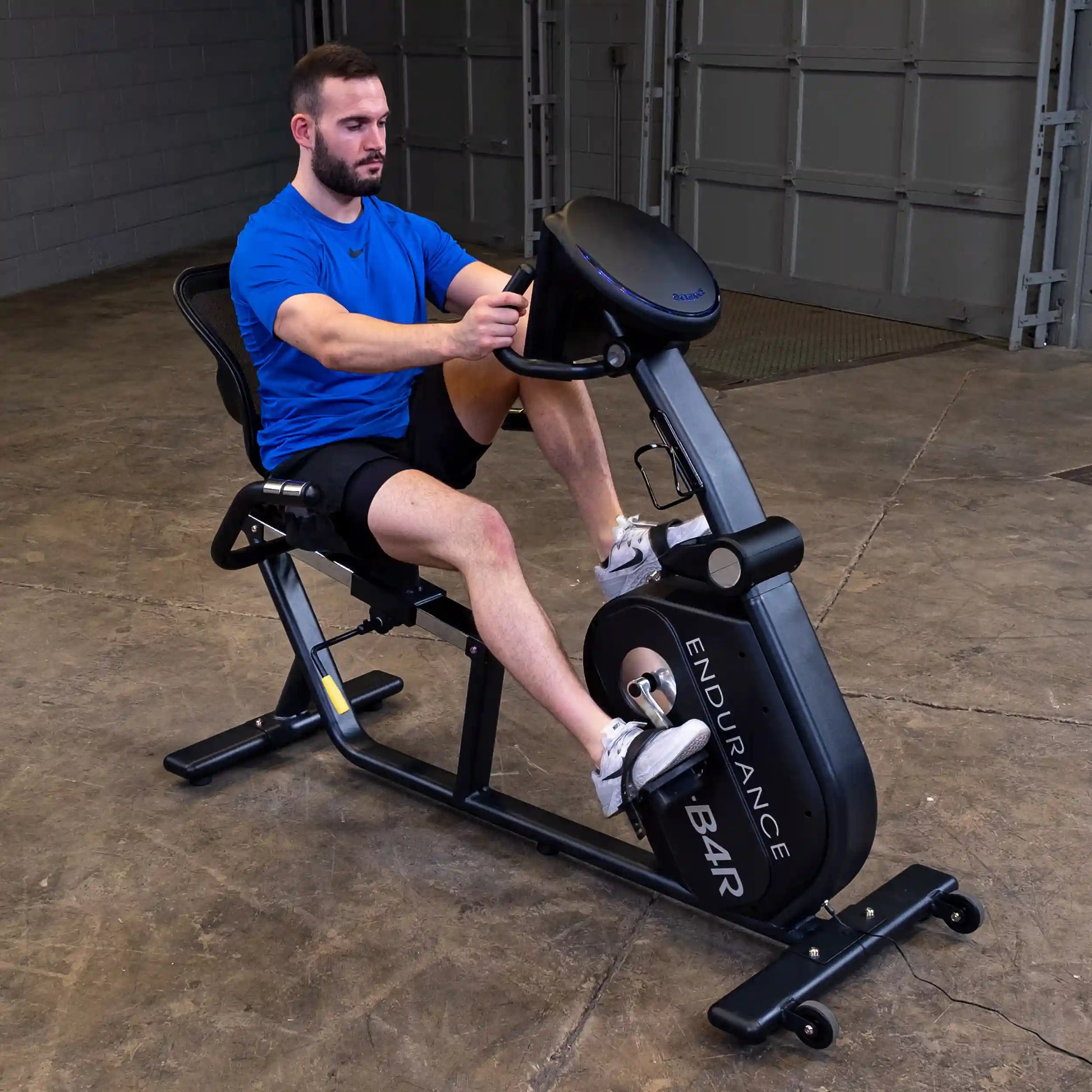 Man exercising on Endurance B4R recumbent bike in a garage.