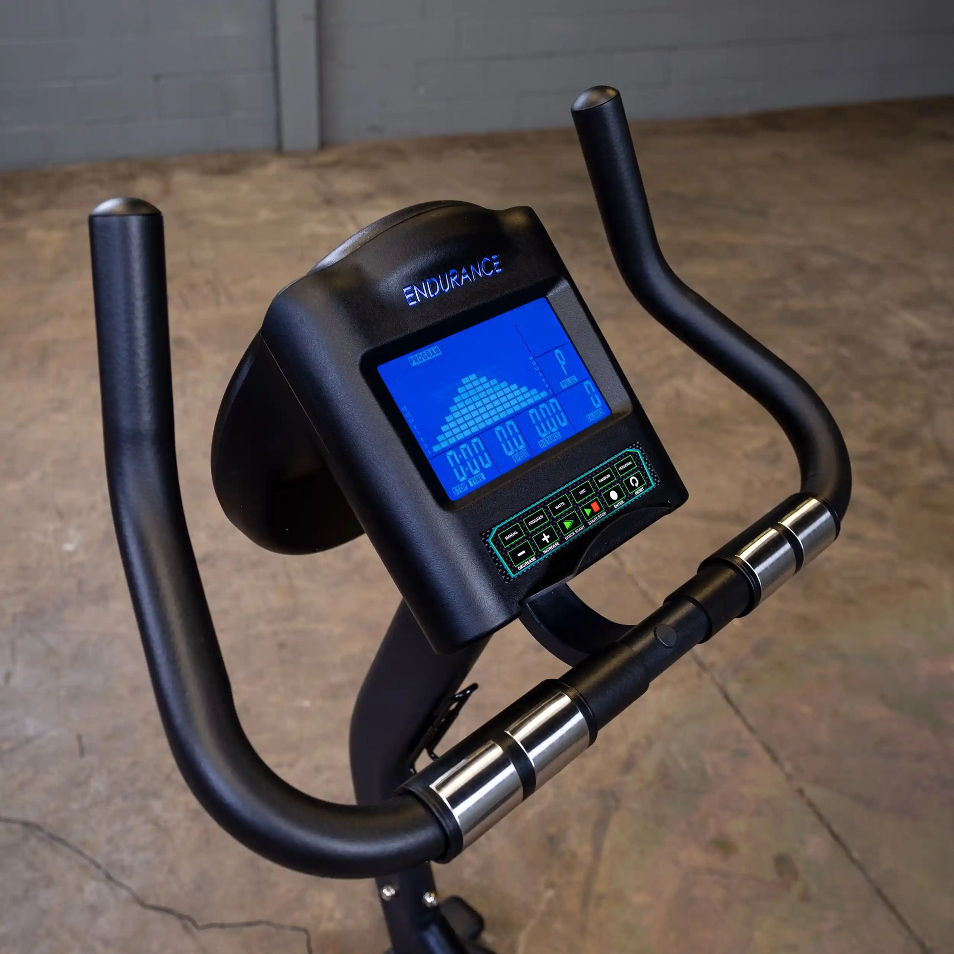 Endurance exercise bike with digital display and black handlebars in an industrial setting.