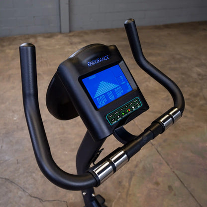 Endurance exercise bike with digital display and black handlebars in an industrial setting.