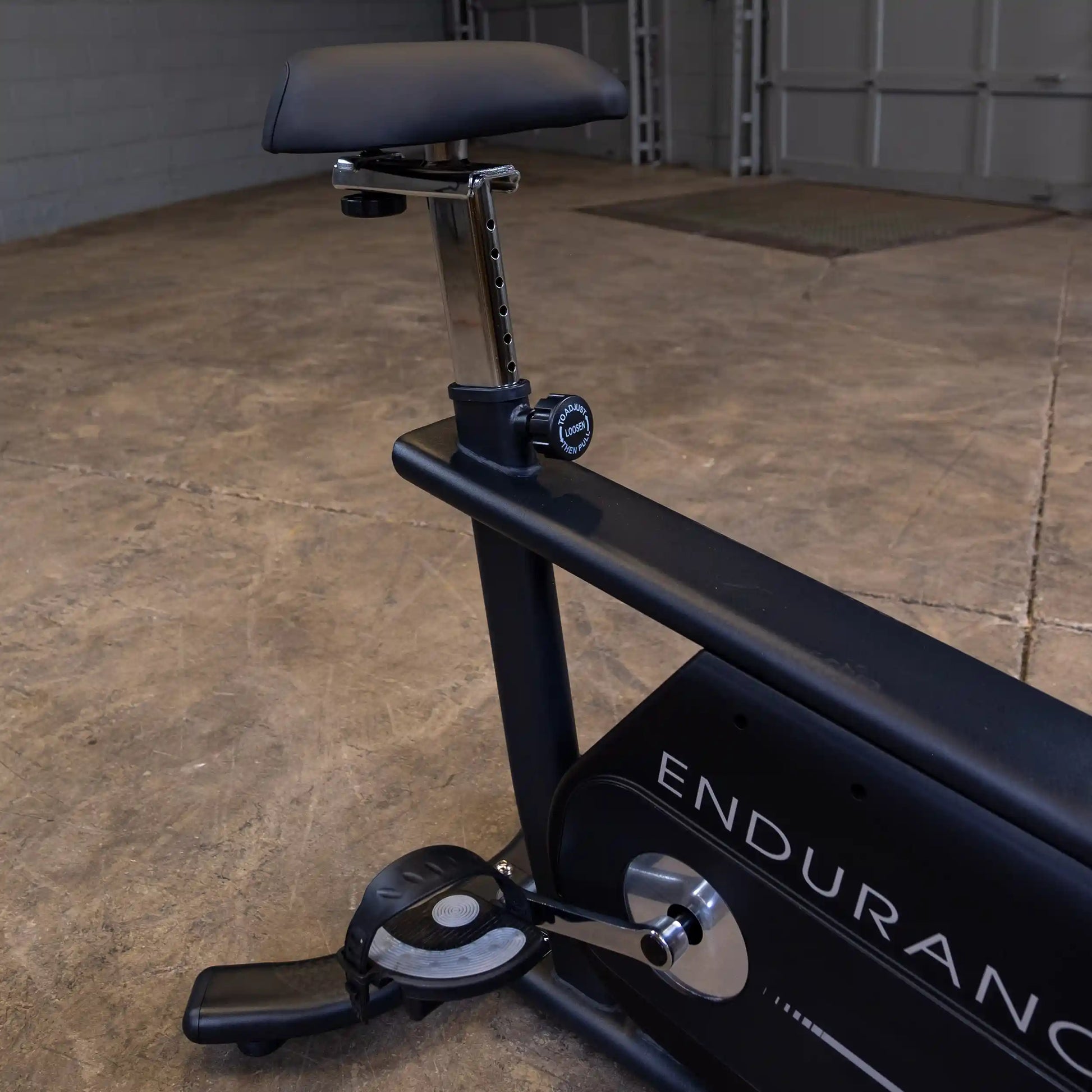 Endurance stationary bike with adjustable seat and black frame in a garage.