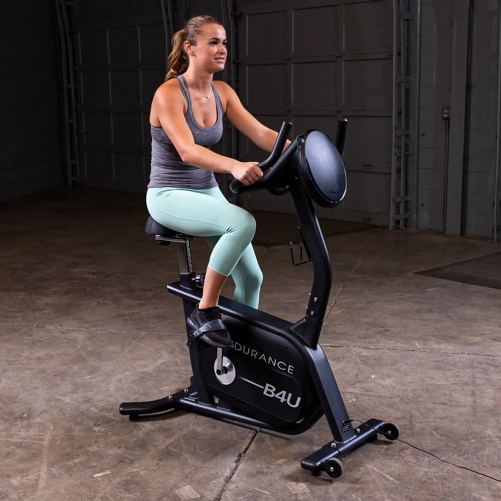 Woman exercising on Endurance B4U stationary bike in a garage.