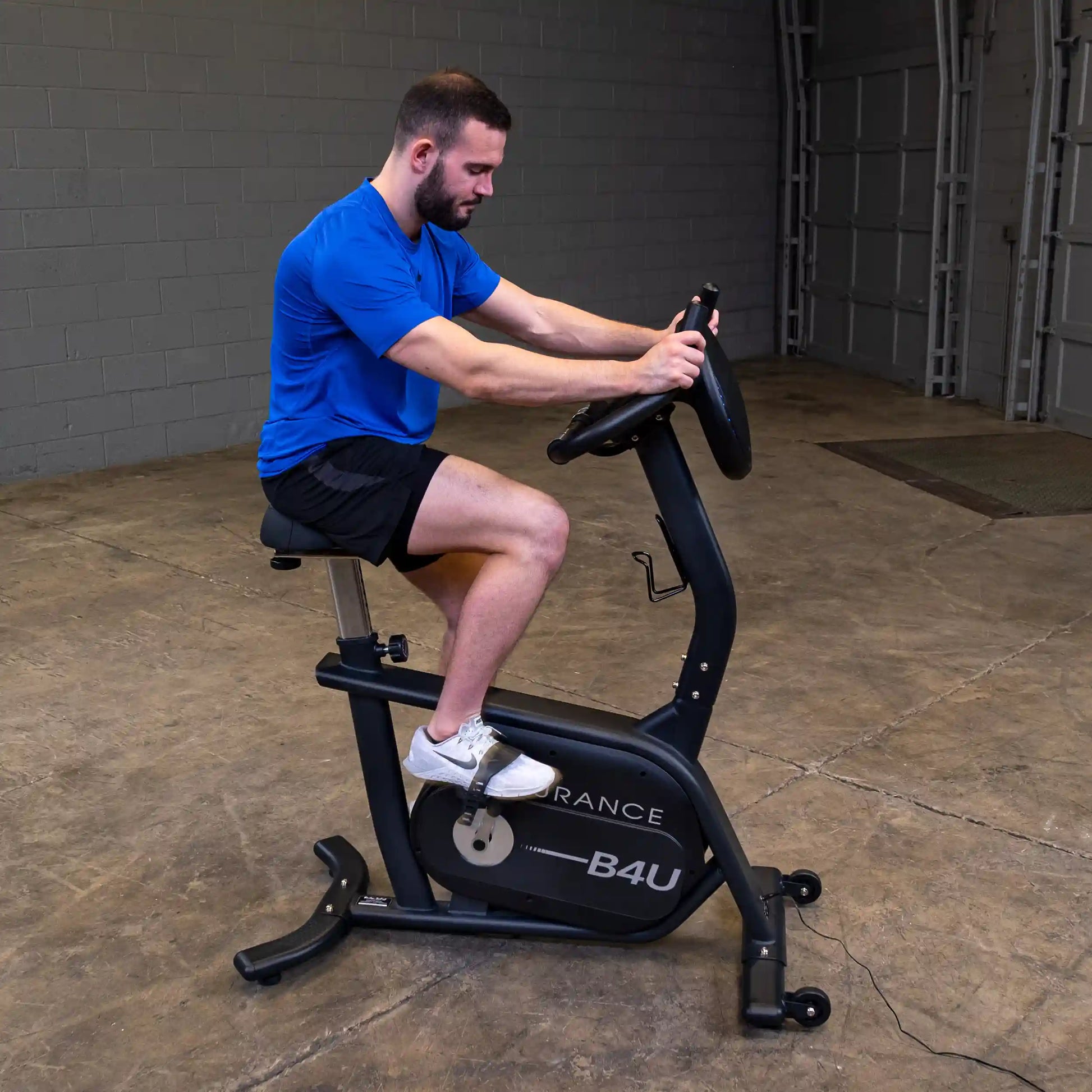 Man exercising on black Endurance B4U stationary bike in a garage.