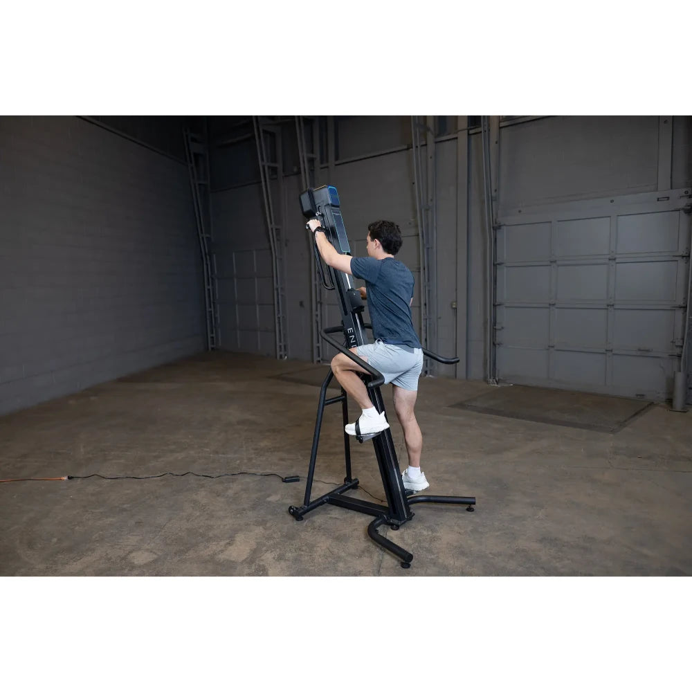Man exercising on black vertical climber machine in spacious gym.