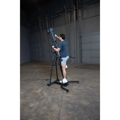 Man using ENDURANCE vertical climber in a gym, wearing blue shirt and white shorts.