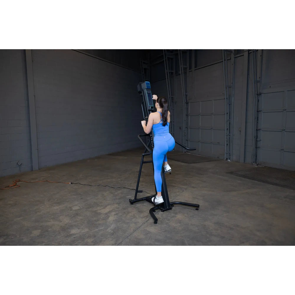 Woman in blue workout gear using a vertical climber machine in a gym.