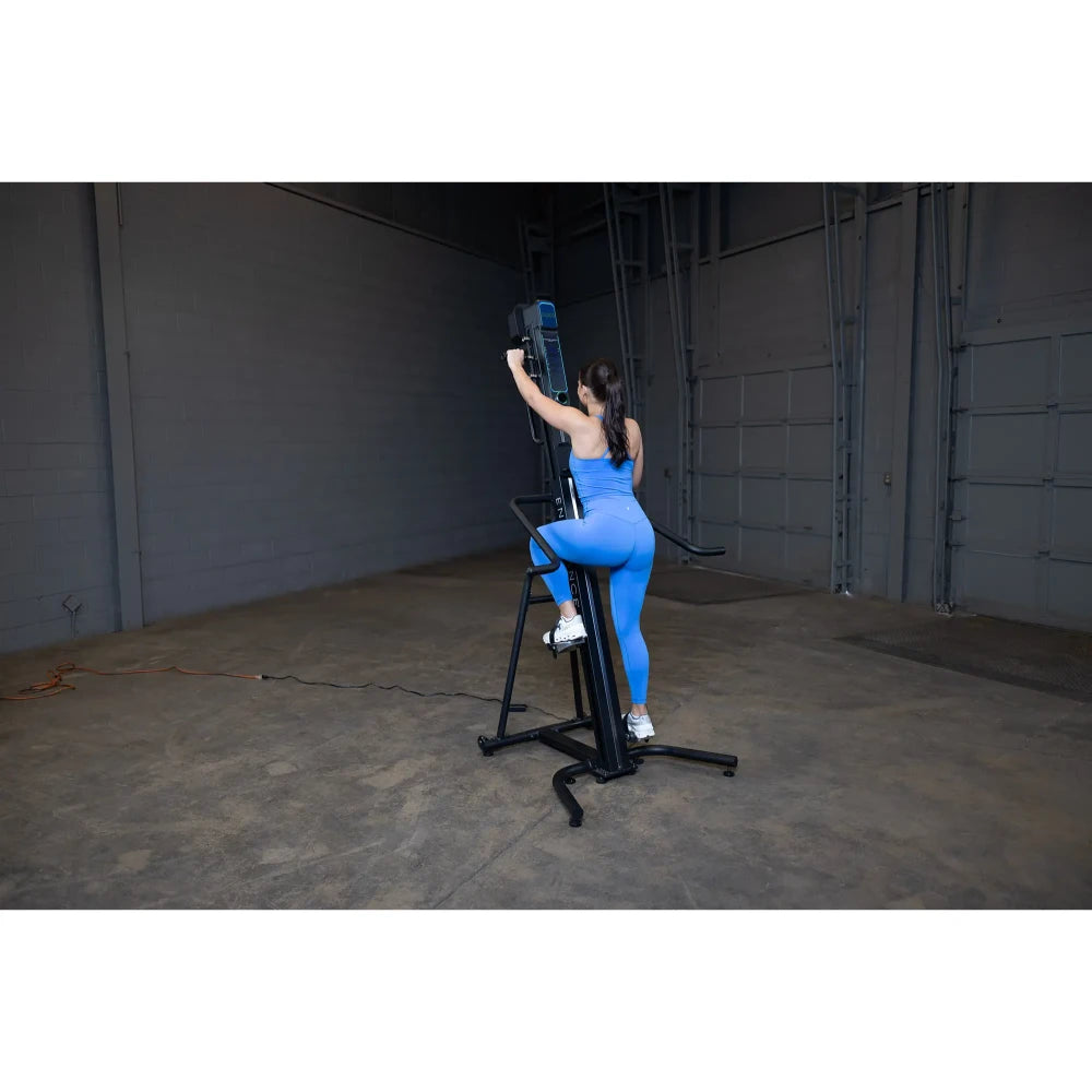 Woman in blue outfit using a vertical climber machine in a gym for fitness training.