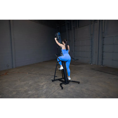 Woman in blue outfit using a vertical climber machine in a gym for fitness training.