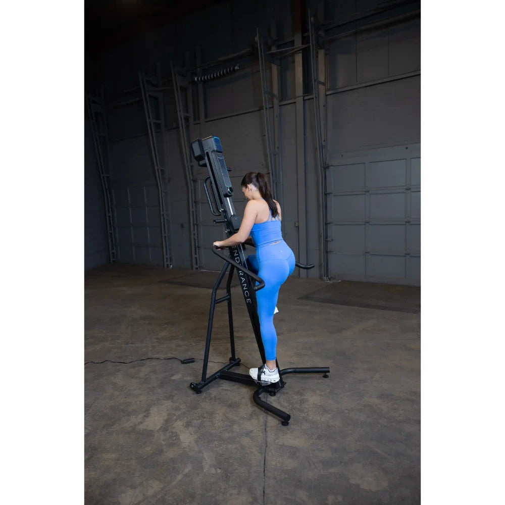 Woman in blue activewear using a black vertical climber machine indoors.