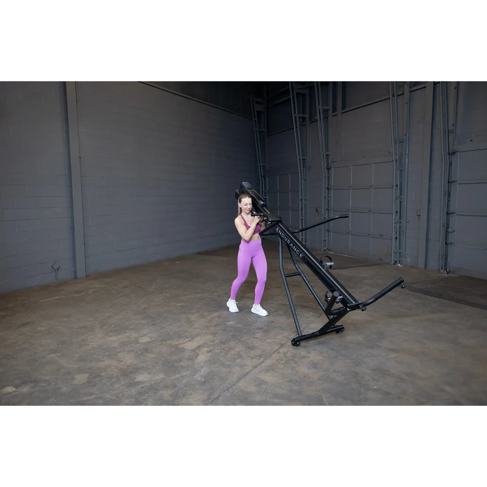 Woman exercising on black Endurance rower in warehouse wearing purple leggings.