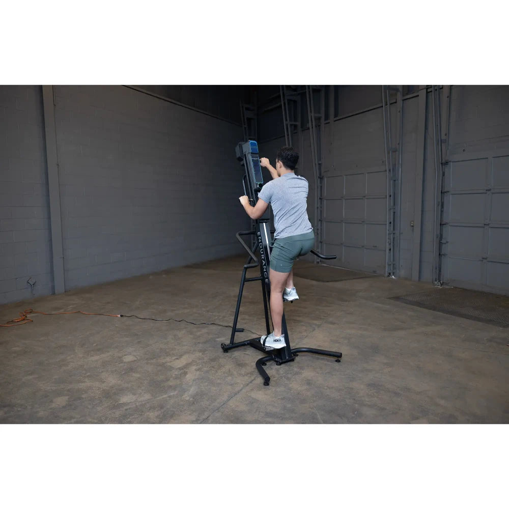 Person using a black vertical climbing machine for exercise in a gym.
