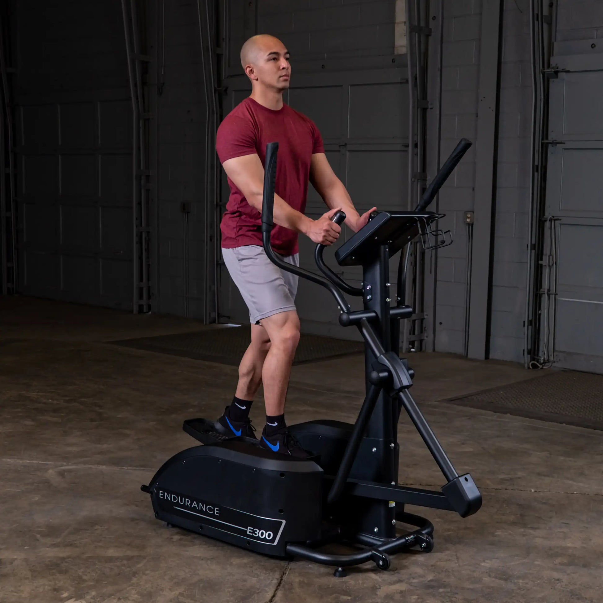 Man exercising on Endurance E300 elliptical trainer in a red shirt indoors.