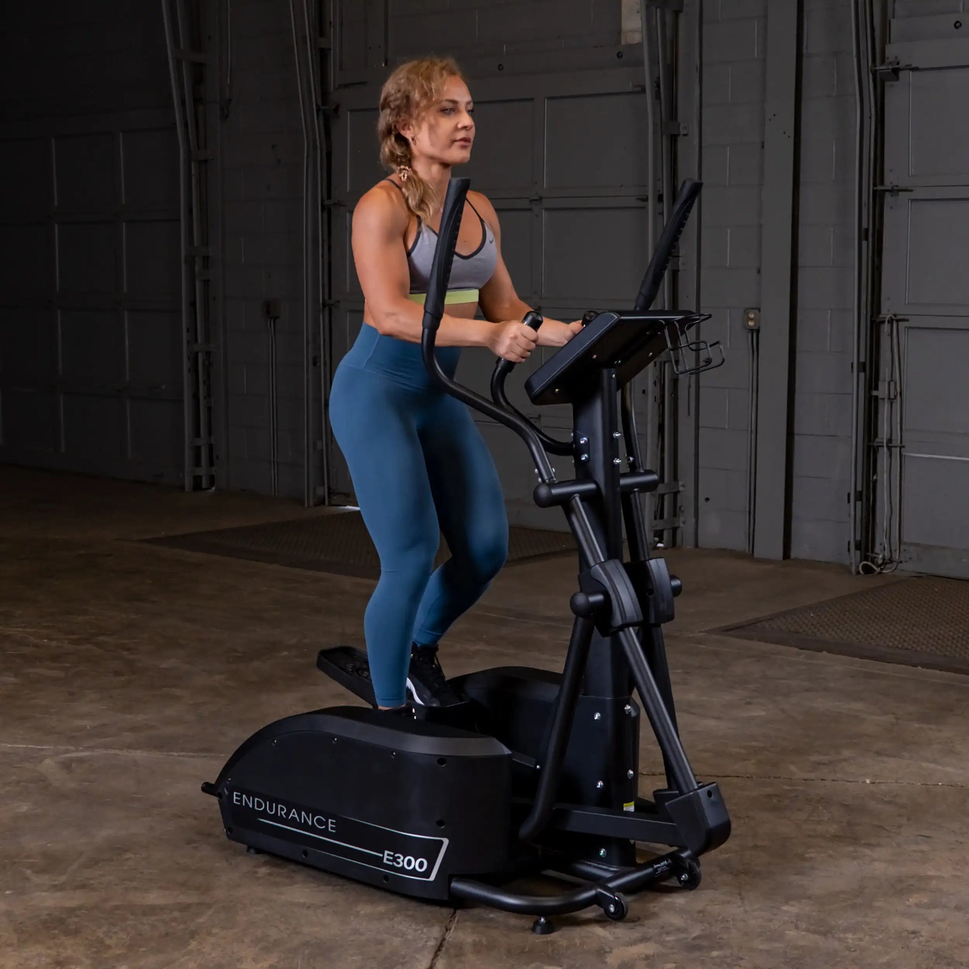 Woman exercising on Endurance E300 elliptical in a gym.