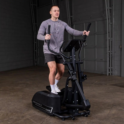 Man exercising on Endurance E400 elliptical trainer in a gray shirt and black shorts.