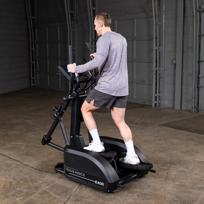 Man exercising on Endurance E400 elliptical in a garage.