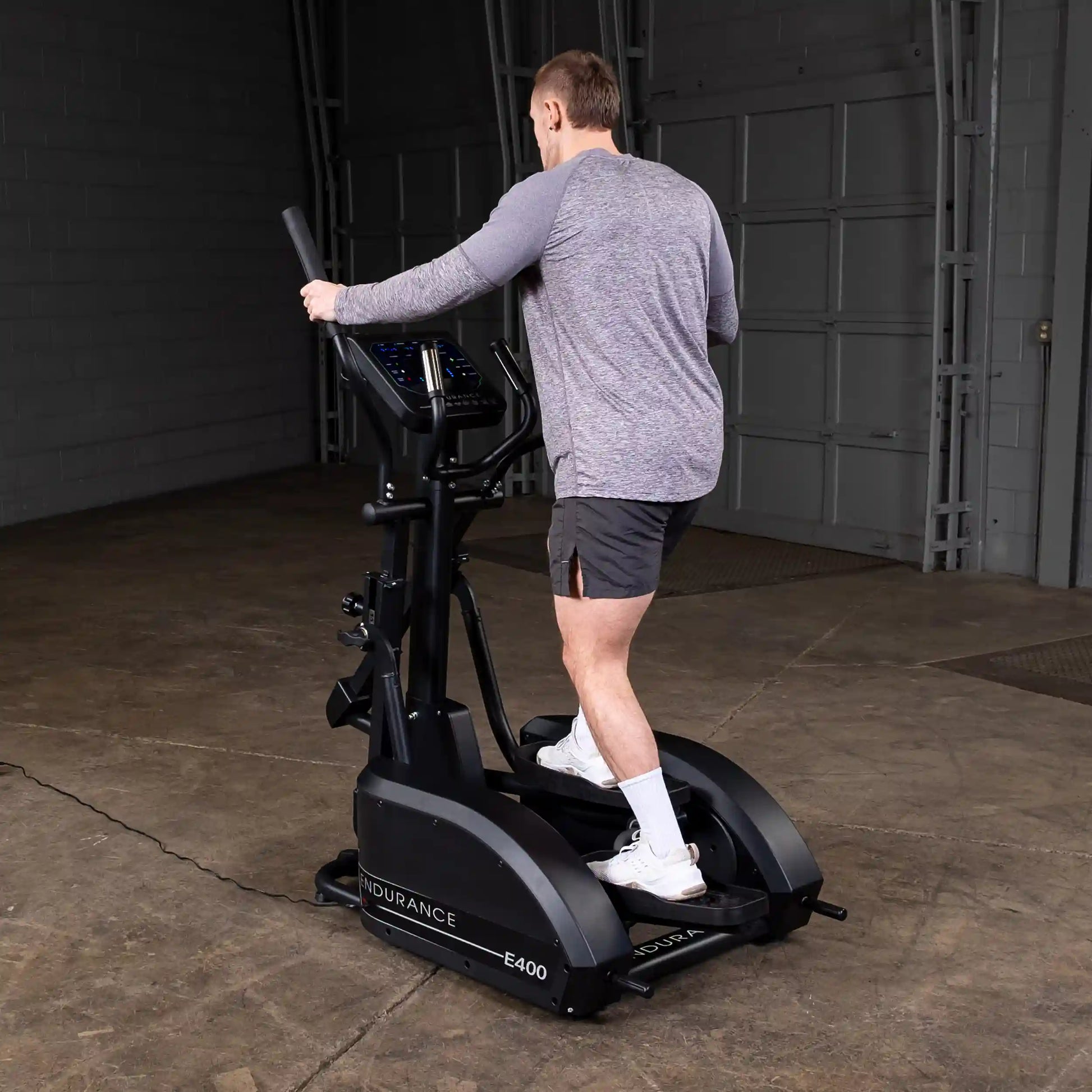 Man using Endurance E400 elliptical trainer in a garage.
