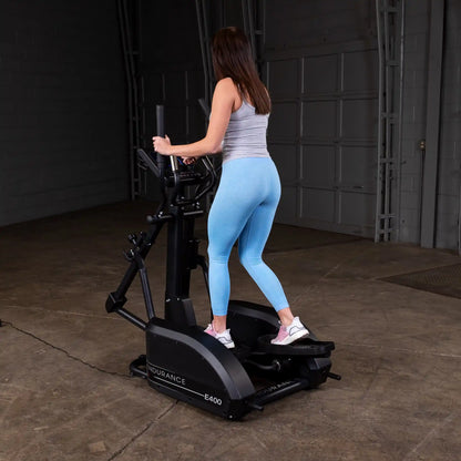 Woman exercising on Endurance E400 elliptical in blue leggings.