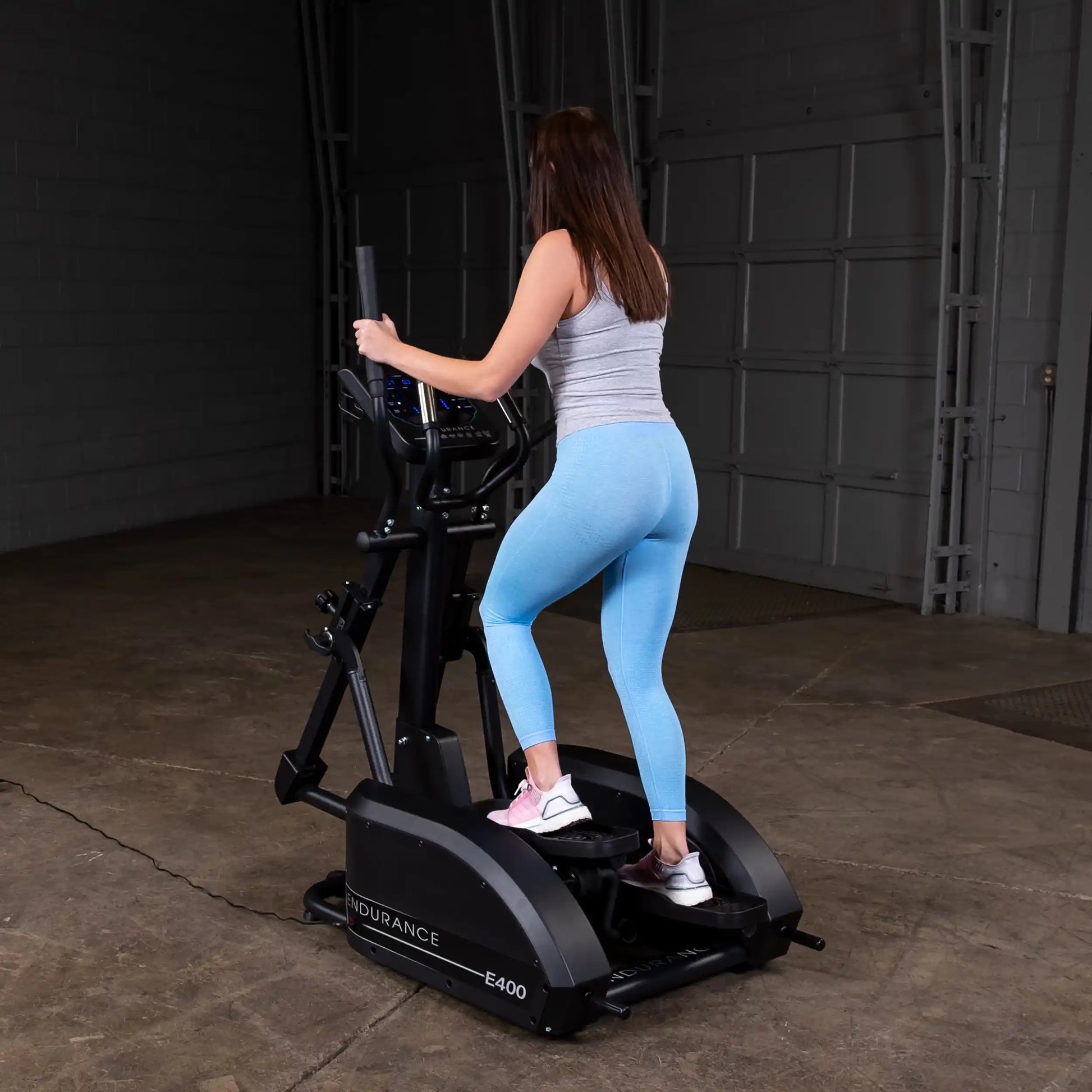 Woman exercising on Endurance E400 elliptical in blue leggings.