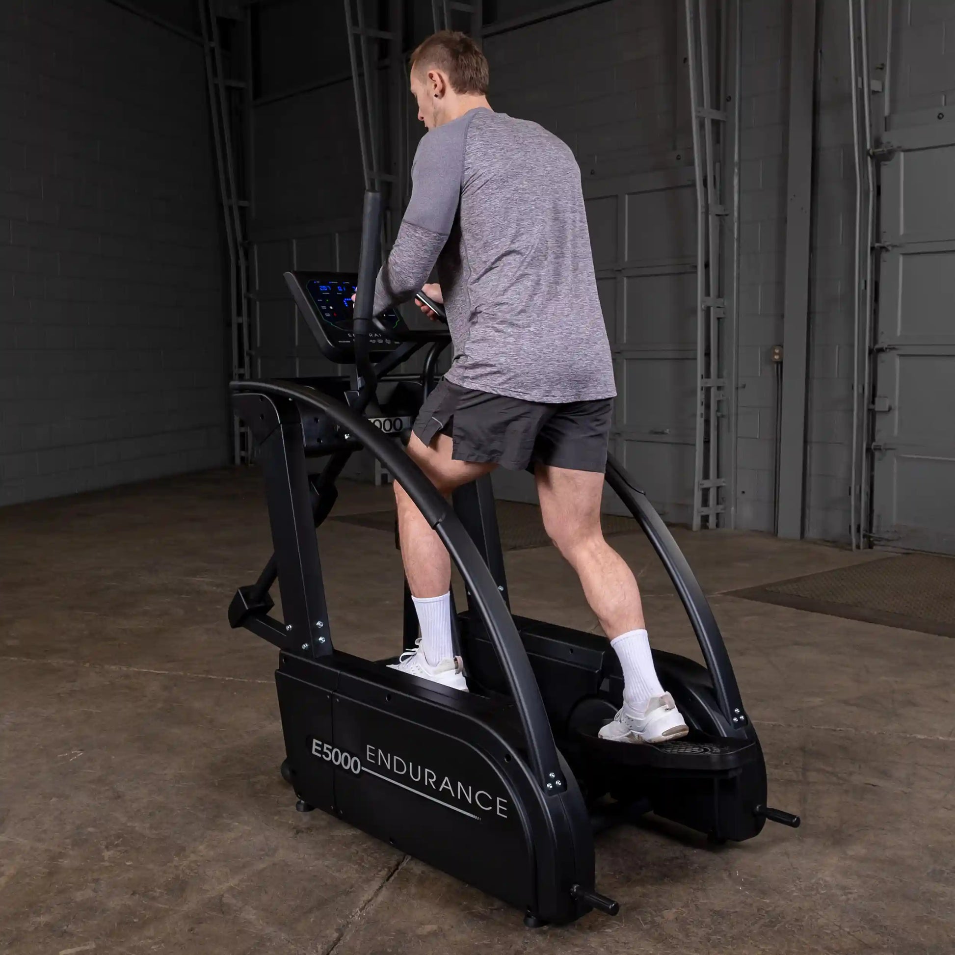 Man using black E5000 Endurance elliptical in a gym.