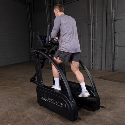 Man using black E5000 Endurance elliptical in a gym.