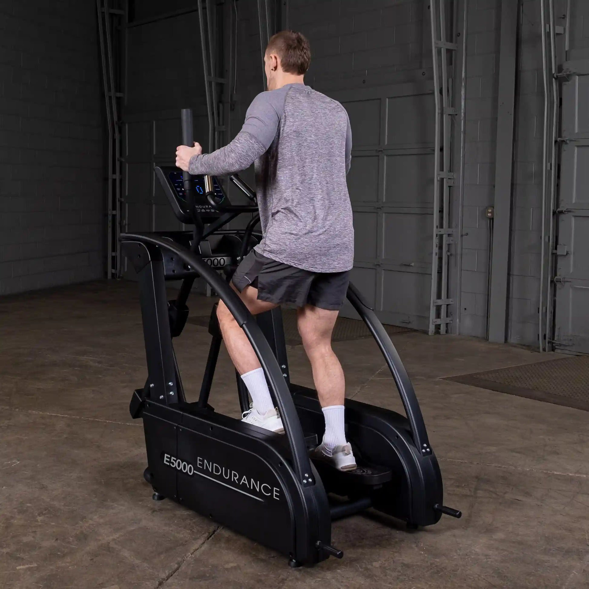 Man exercising on Endurance E5000 elliptical trainer in a gym setting.