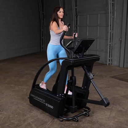 Woman exercising on Endurance E5000 elliptical trainer in a gray top and blue leggings.