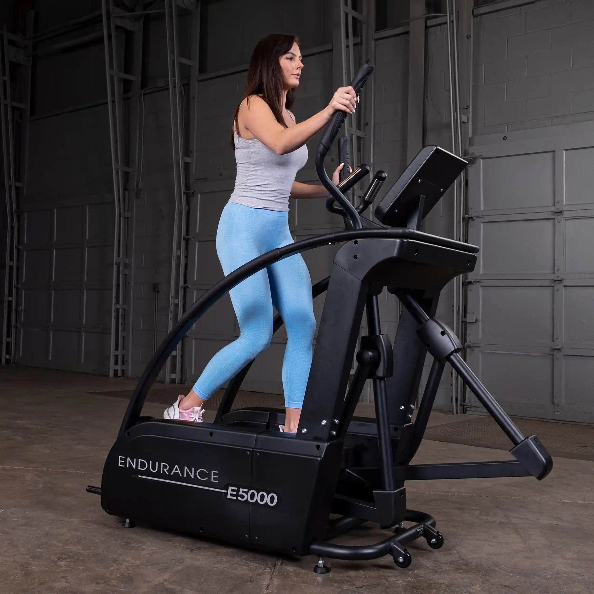Woman exercising on Endurance E5000 elliptical trainer in a gym.