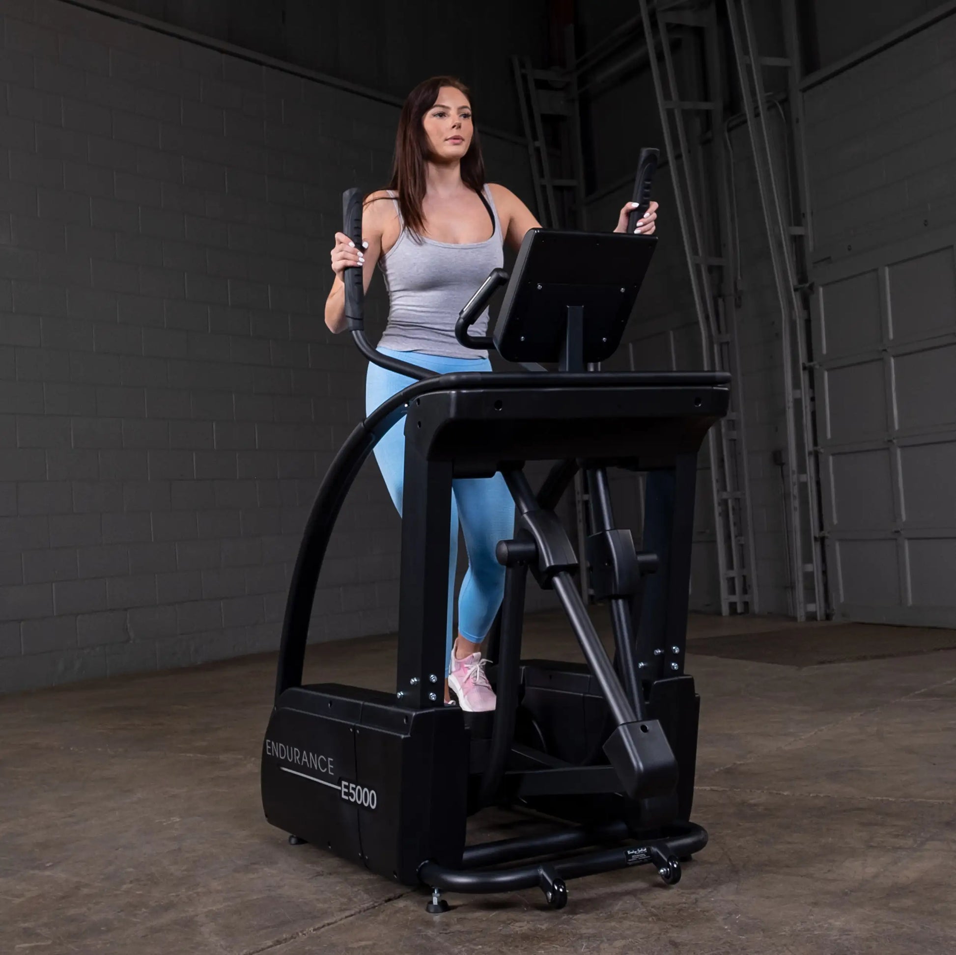 Woman exercising on Endurance E5000 elliptical in a gym.