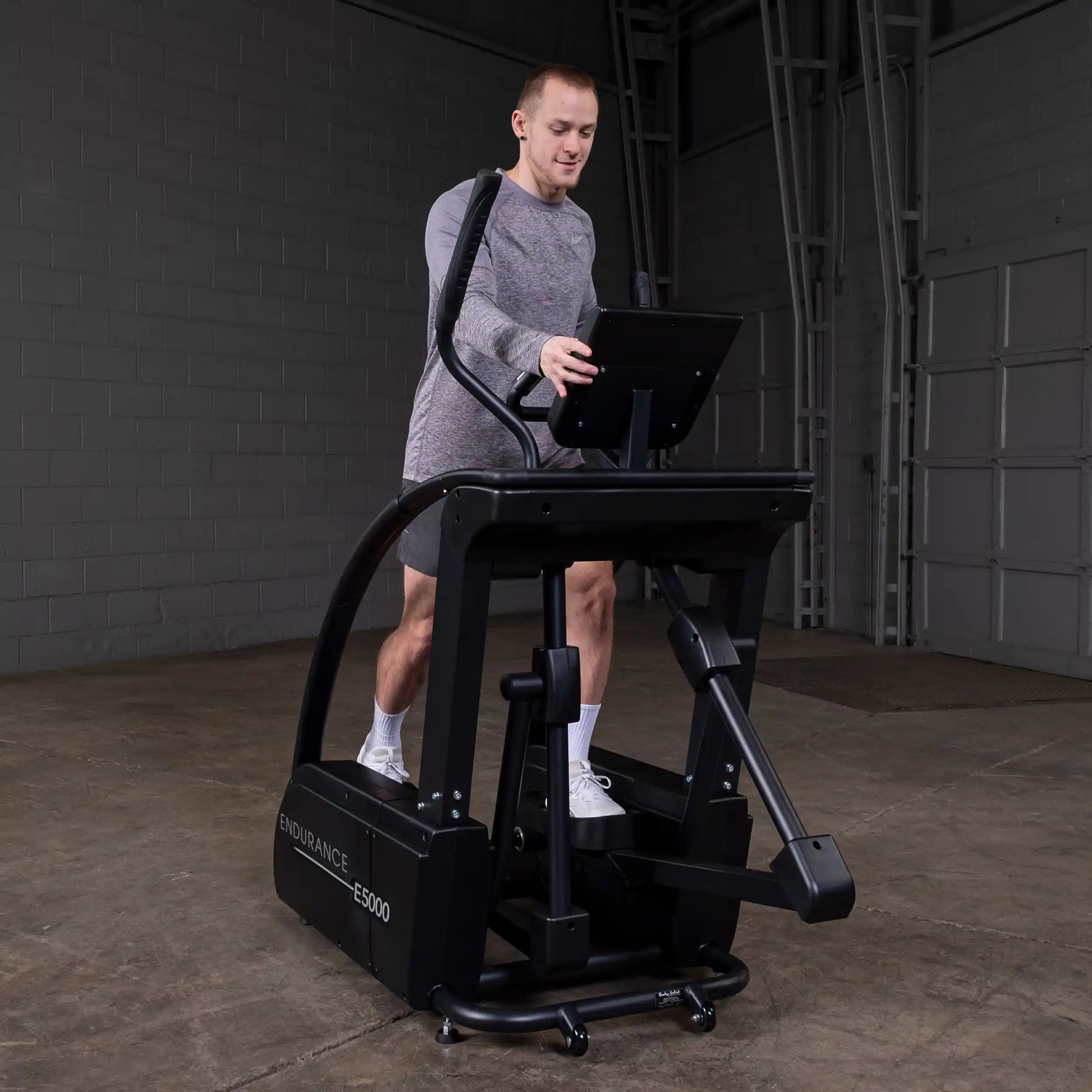 Man using Endurance E5000 elliptical in a gray room.