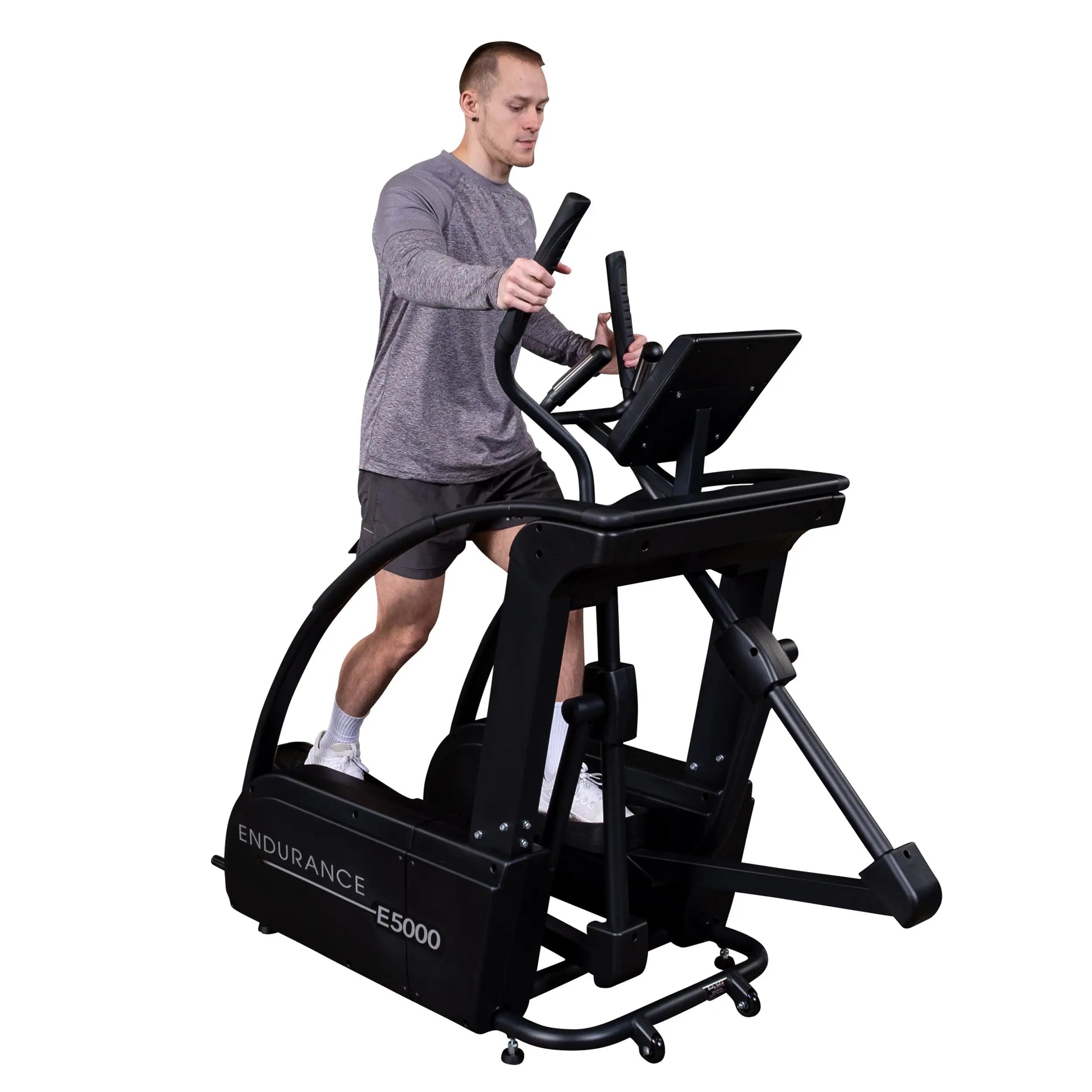 Man exercising on Endurance E5000 elliptical machine, wearing gray shirt and shorts.