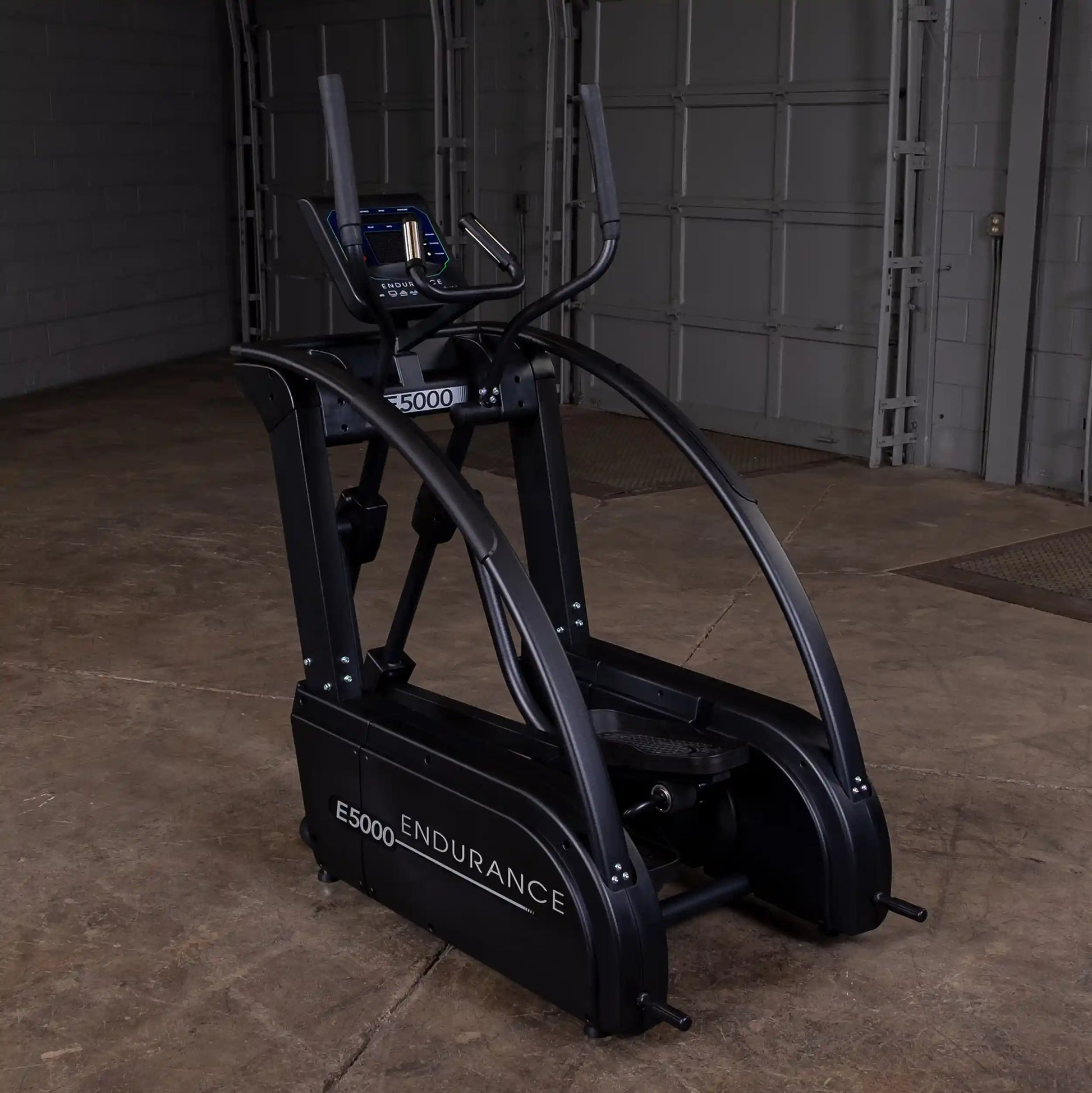 Endurance E5000 elliptical in dark finish, featuring dual curved handlebars in a spacious garage setting.