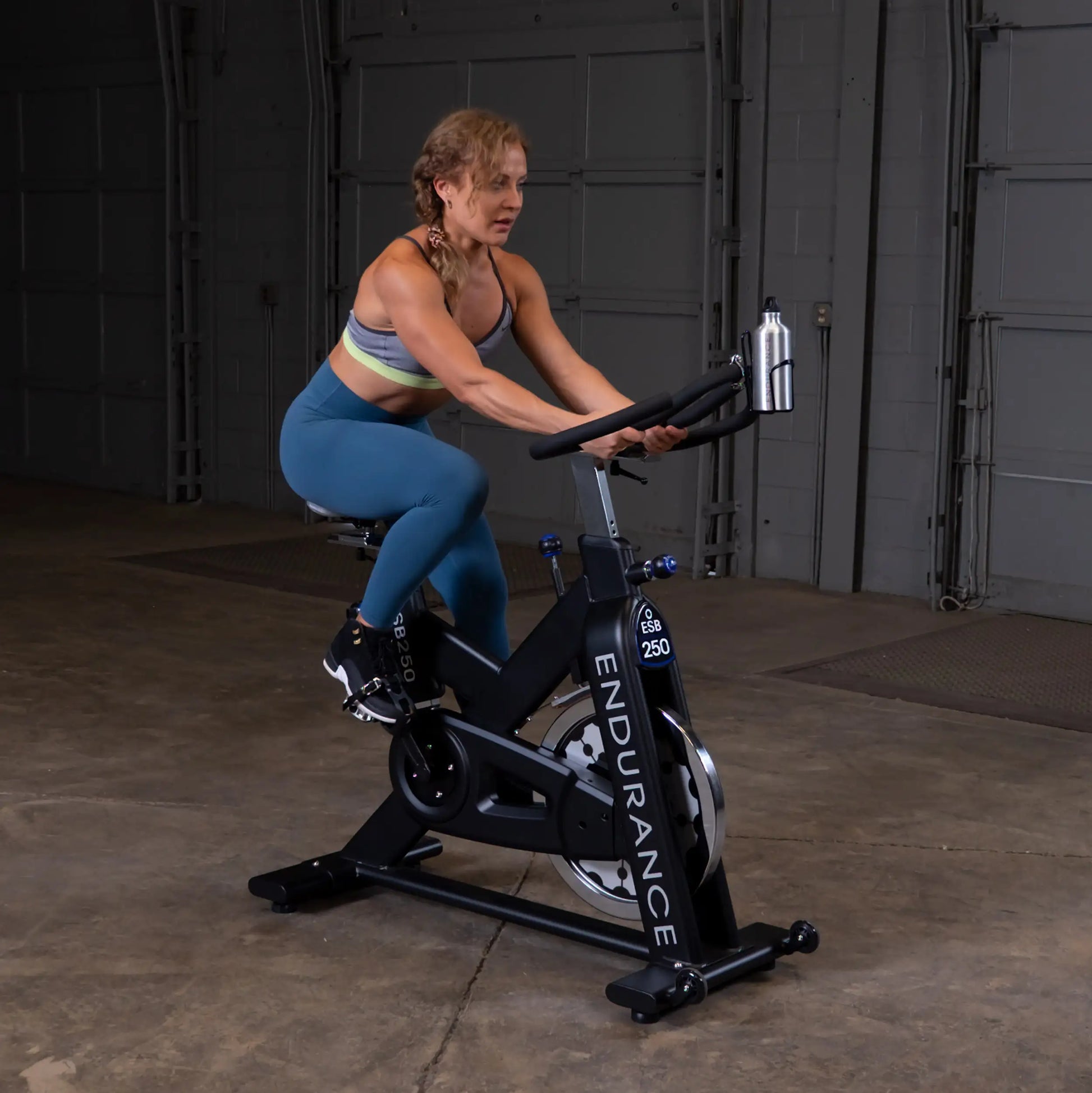 Woman exercising on Endurance ESB250 indoor cycling bike in a gym.
