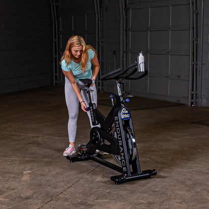 Woman adjusting seat on black Endurance ESB250 exercise bike in a garage.