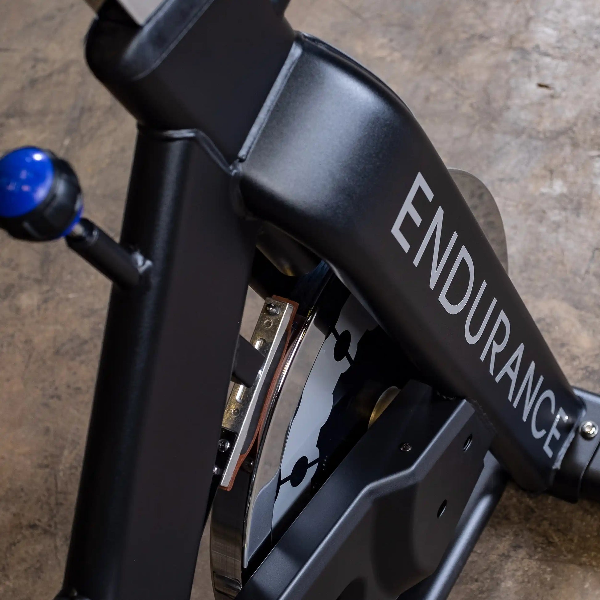 Endurance exercise bike in black with visible flywheel and blue adjustment knob.