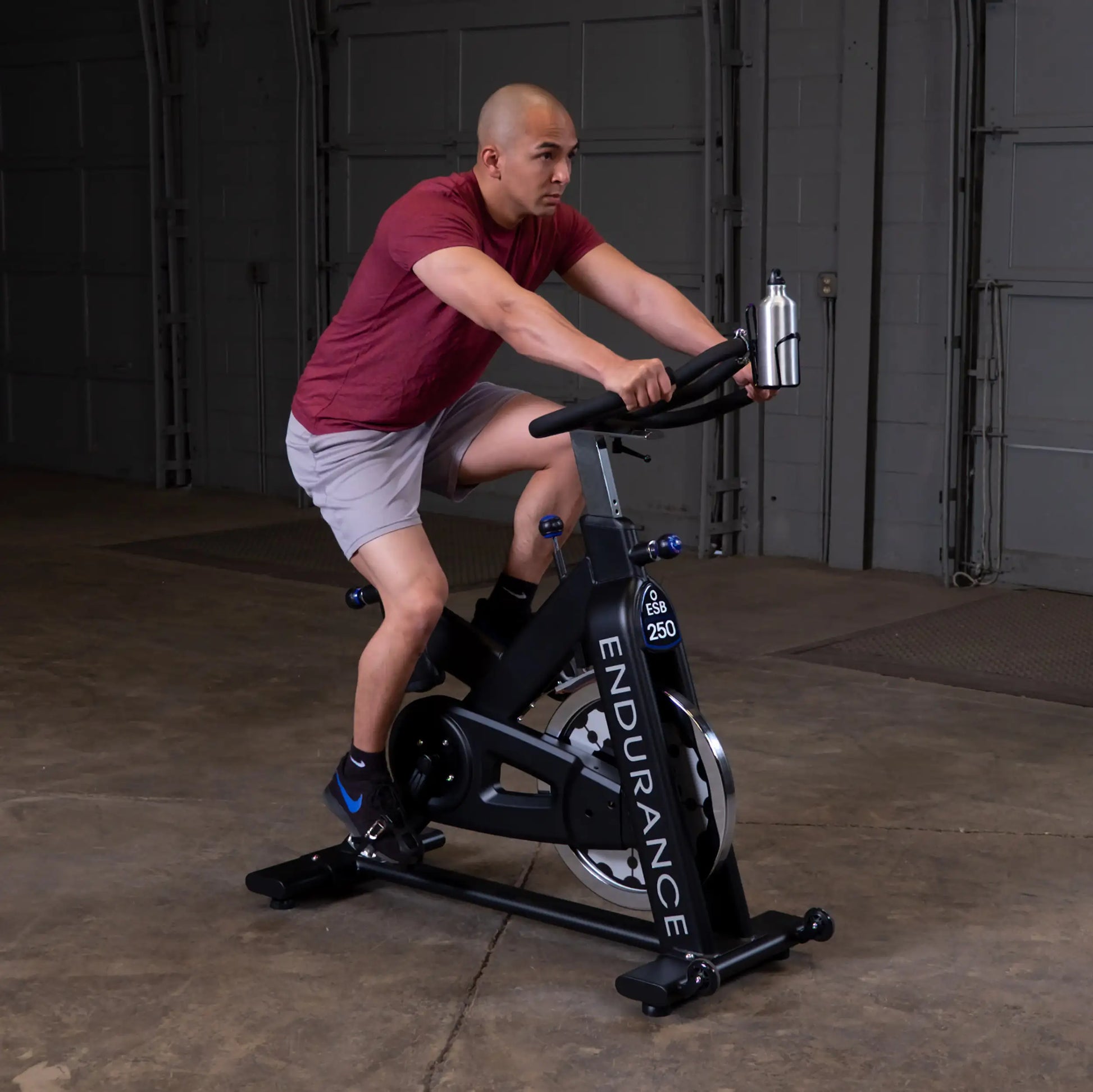 Man cycling on Endurance ESB 250 exercise bike in a garage.