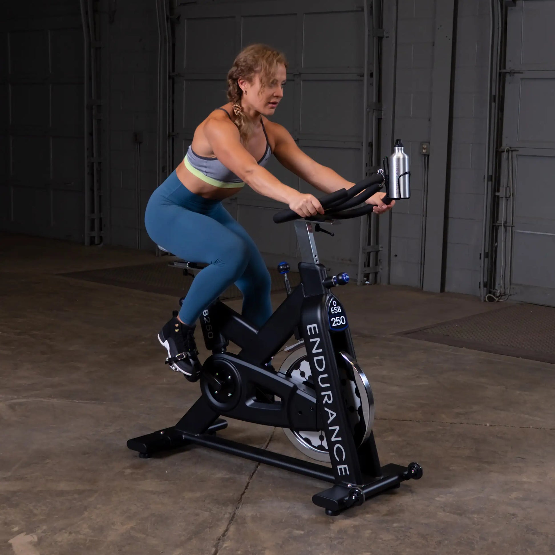 Woman exercising on Endurance ESB250 indoor cycling bike in a garage.