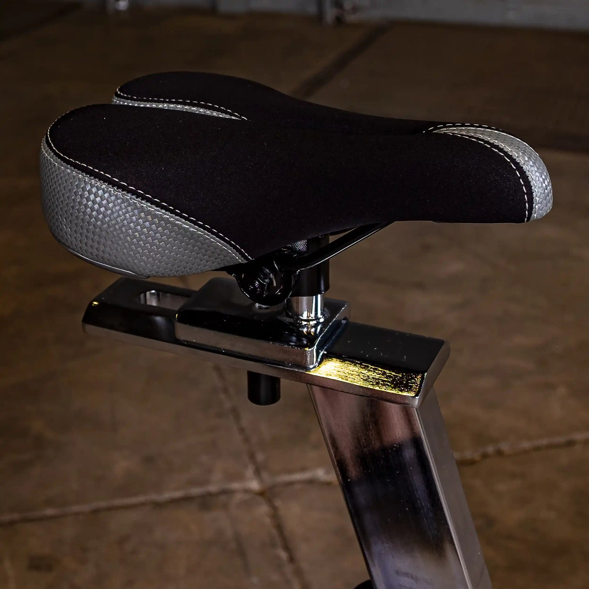 Black and gray bike seat with ergonomic design on a metallic post.