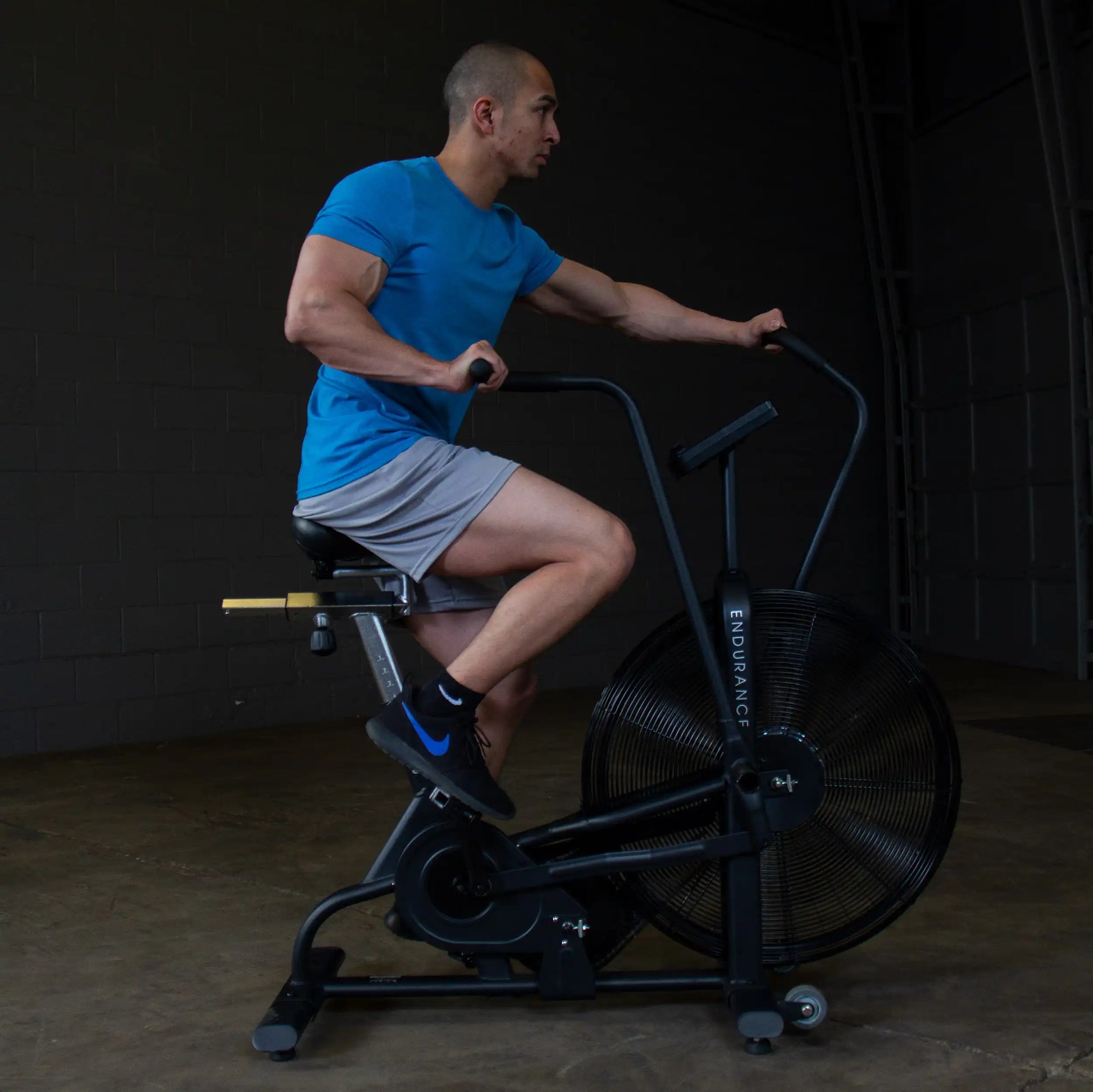 Man exercising on black Endurance air bike in gym.