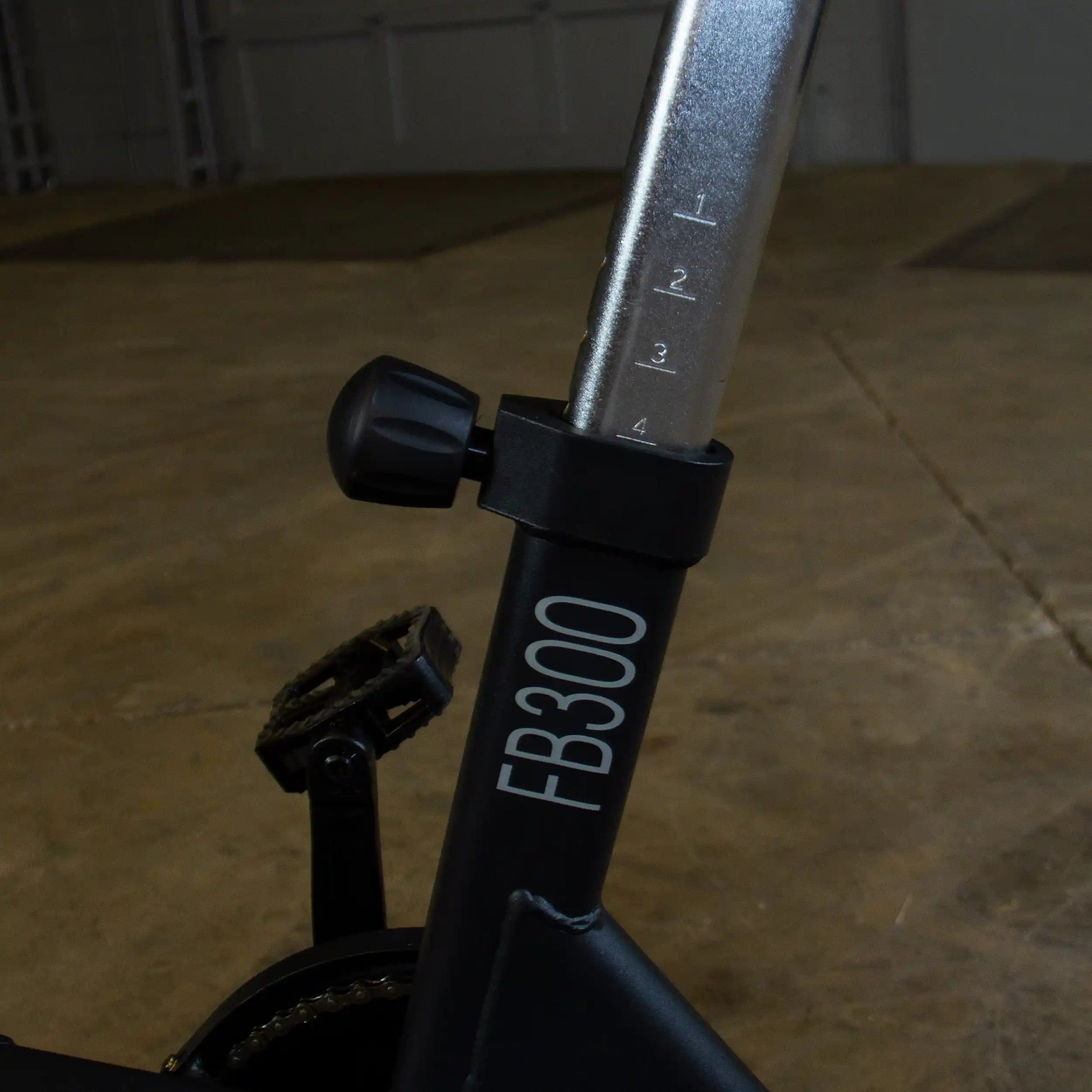 FB300 exercise bike seat post with adjustable height in a dark garage.