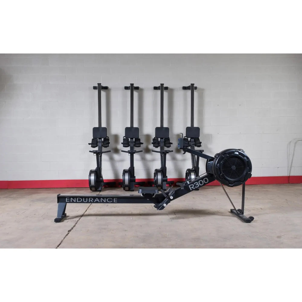 Endurance R300 rowing machine in black with four seats against a gray wall.