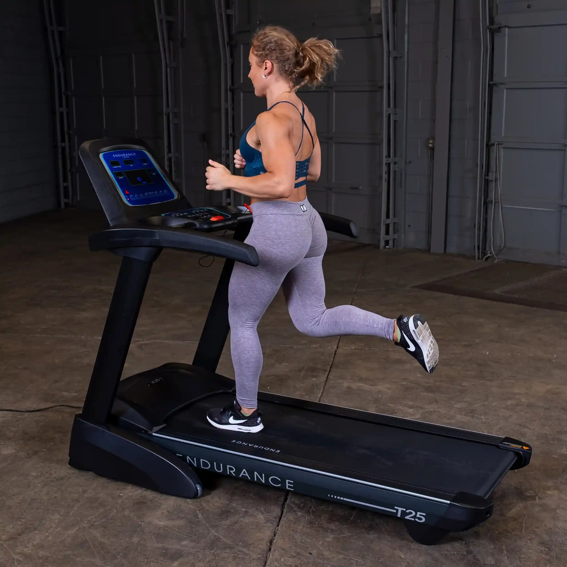 Woman running on Endurance T25 treadmill in gray leggings and black sneakers.