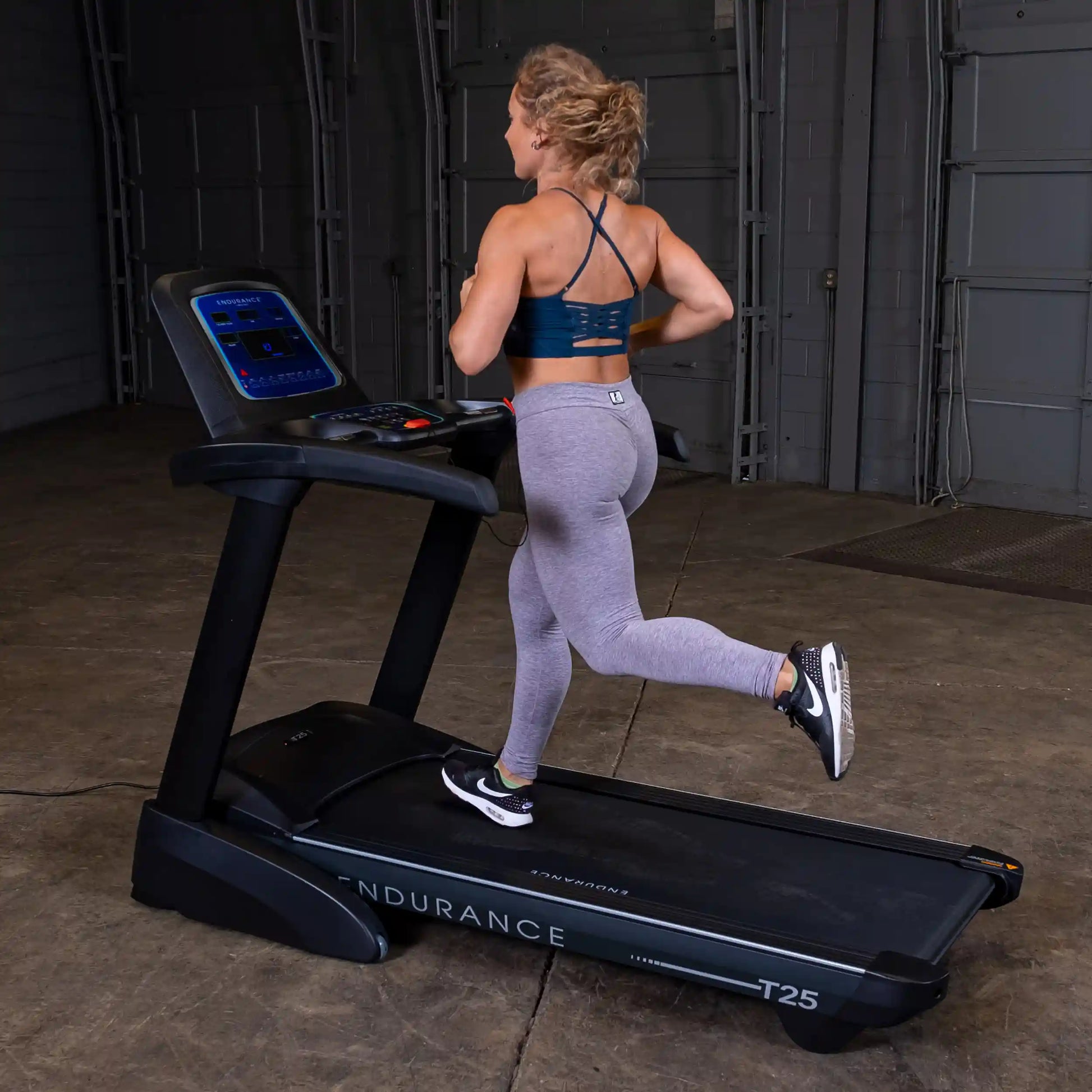 Woman jogging on Endurance T25 treadmill in gray leggings.
