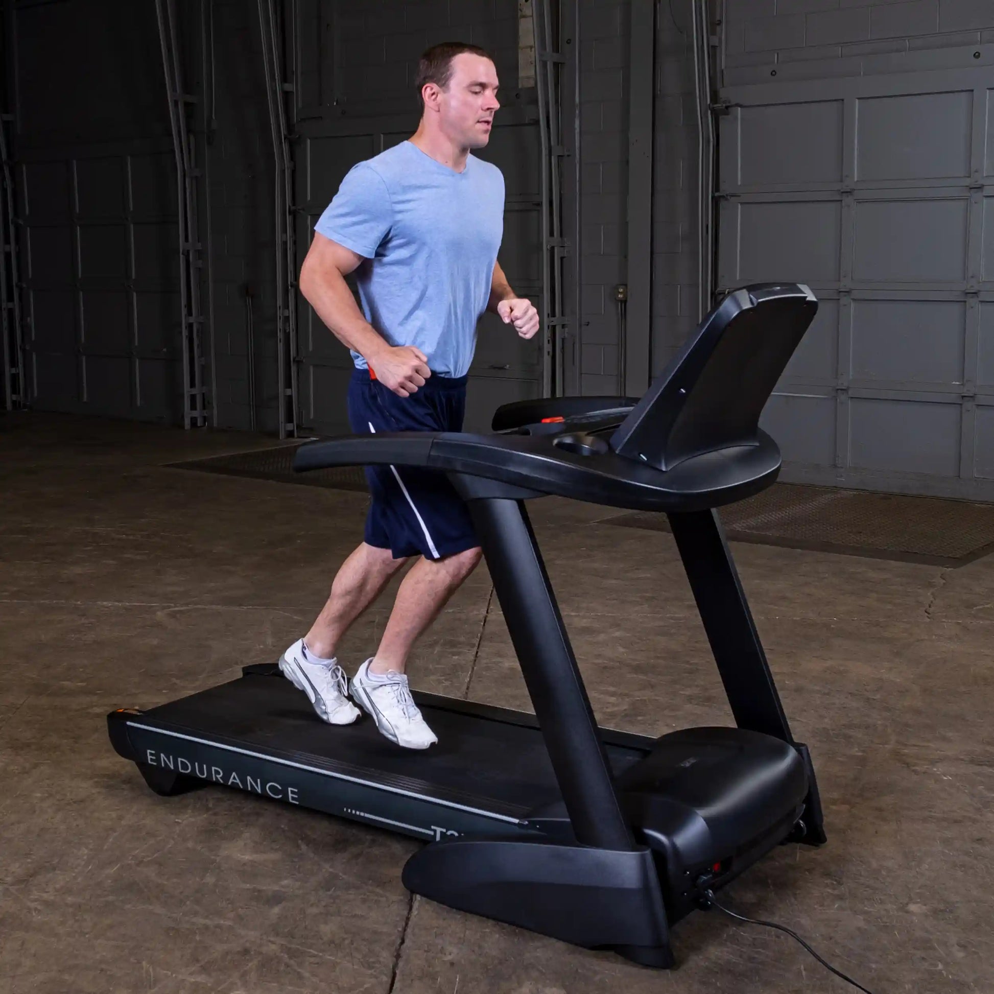 Man jogging on black Endurance treadmill in a garage setting.