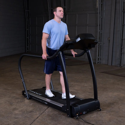 Man walking on Endurance T50 treadmill in a gym, wearing blue shirt and navy shorts.