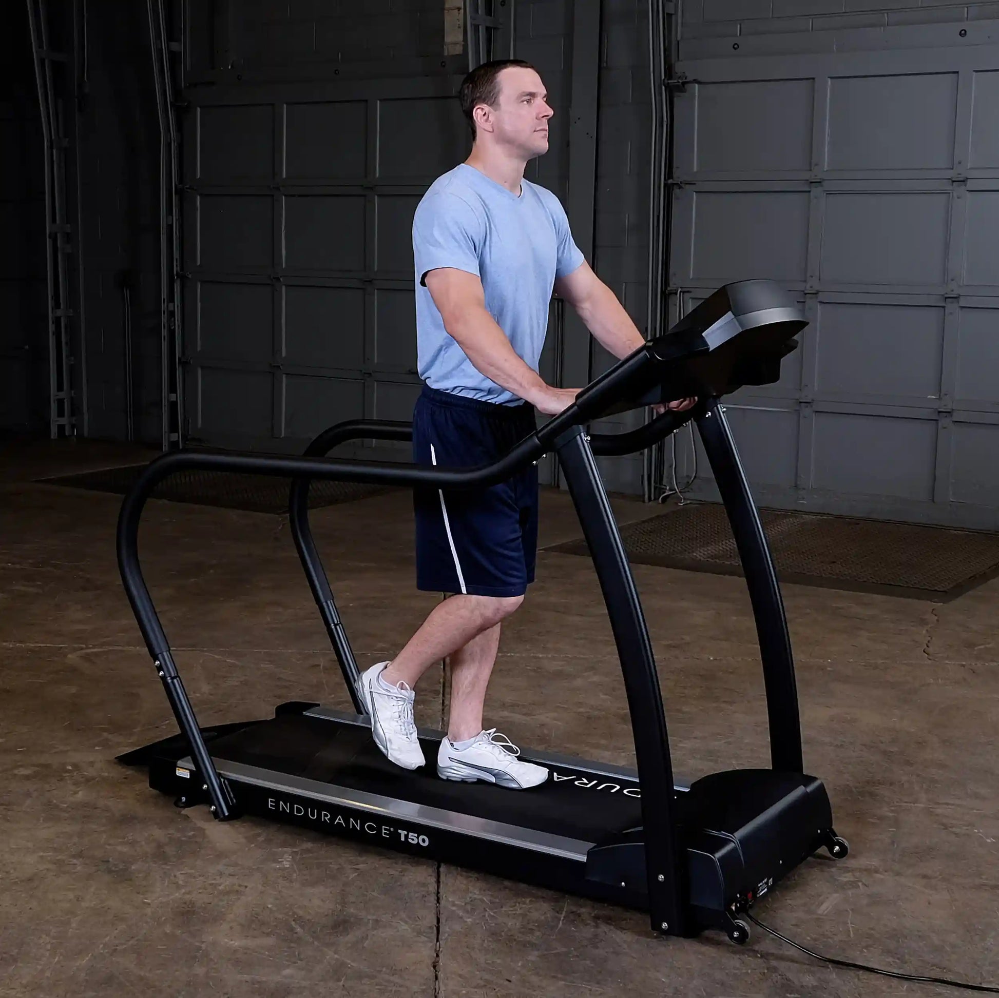 Man exercising on Endurance T50 treadmill in a garage setting.